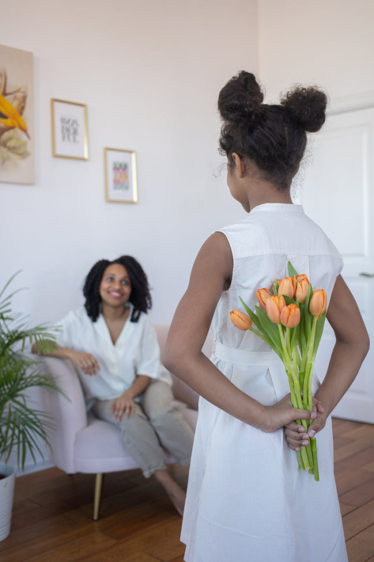 a girl surprising her mother with a bouquet of flowers