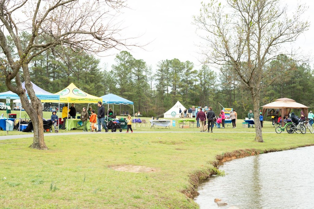 MOUNTAINFILM 2025-38 - The Cultural Current Outdoor community fair at a park by a pond with colorful tents and families walking